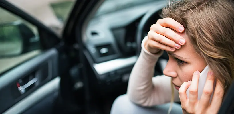 A woman holding her head after a car wreck and now seeking help from a car accident lawyer.